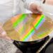 Gloved technician holding a patterned silicon wafer in a cleanroom