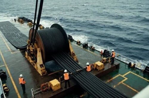 Workers oversee a large subsea cable spool on a ship deck