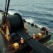 Workers oversee a large subsea cable spool on a ship deck